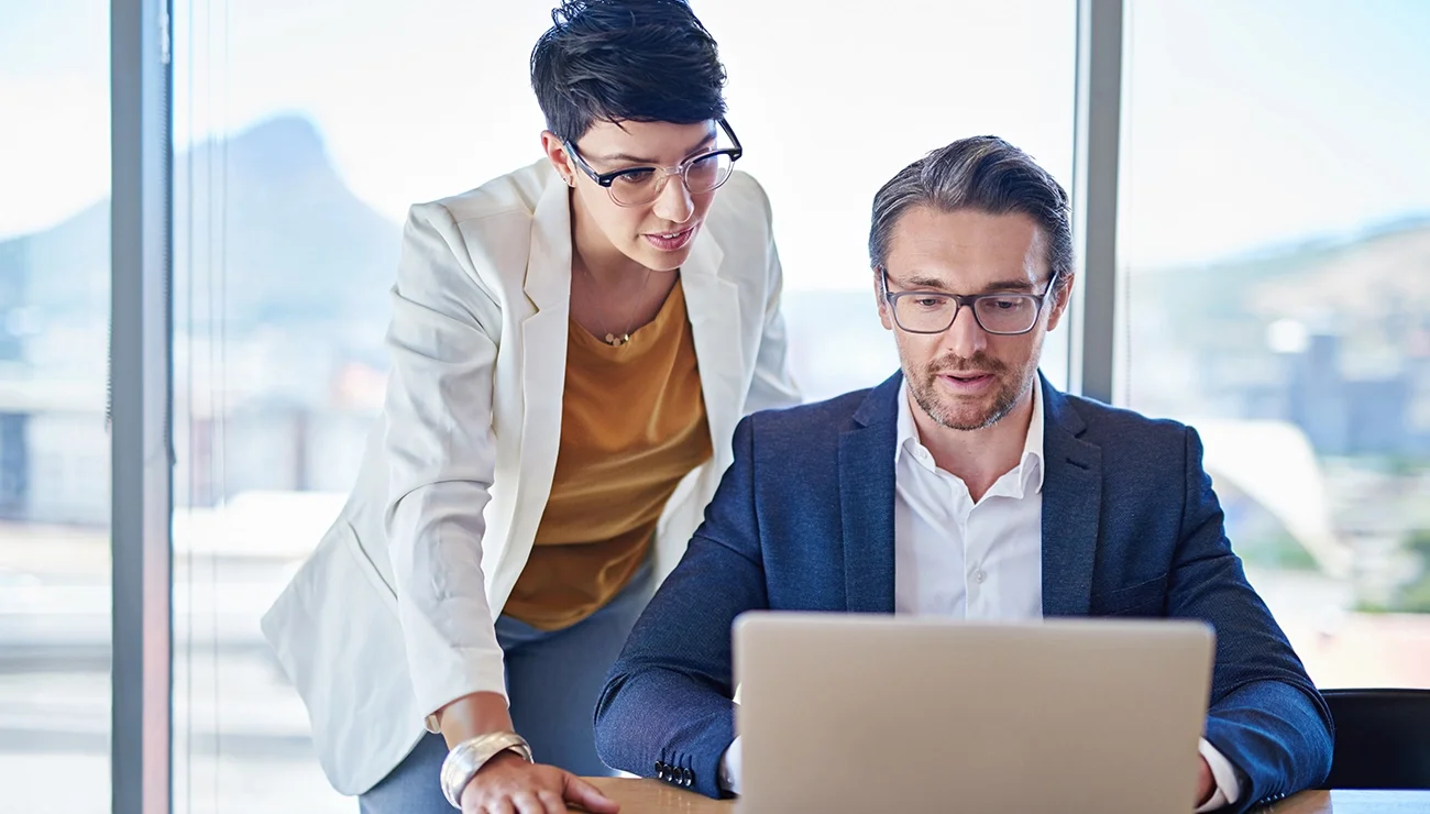 Twee personen werken samen op een laptop.