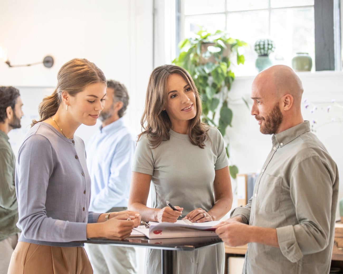 Drie deelnemers hebben overleg aan een statafel