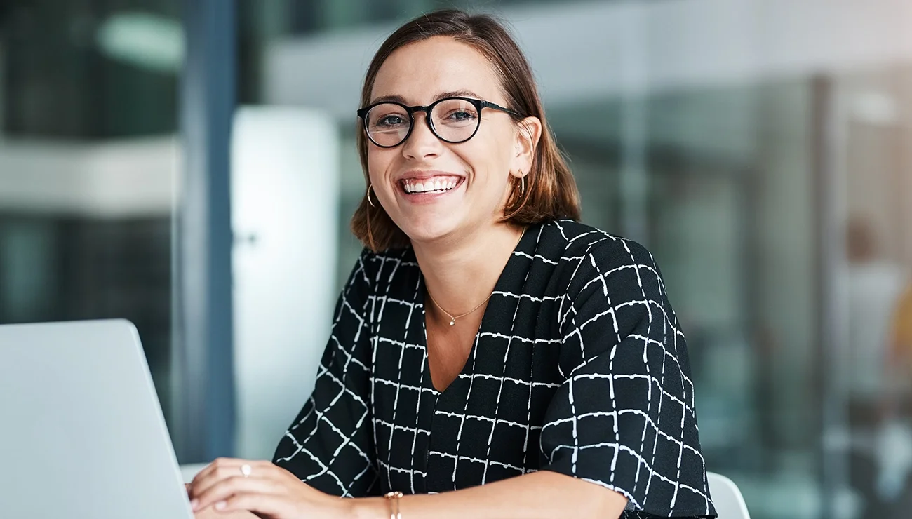 Vrouw met bril achter laptop op kantoor