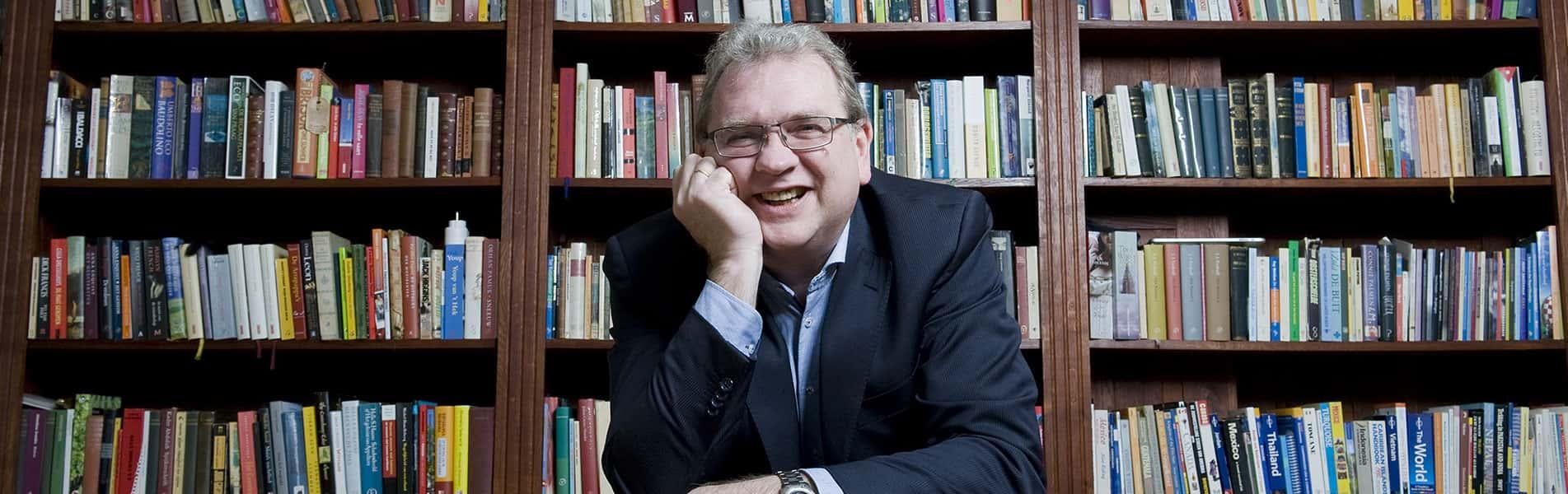 Docent Martin Koekkoek voor een grote boekenkast