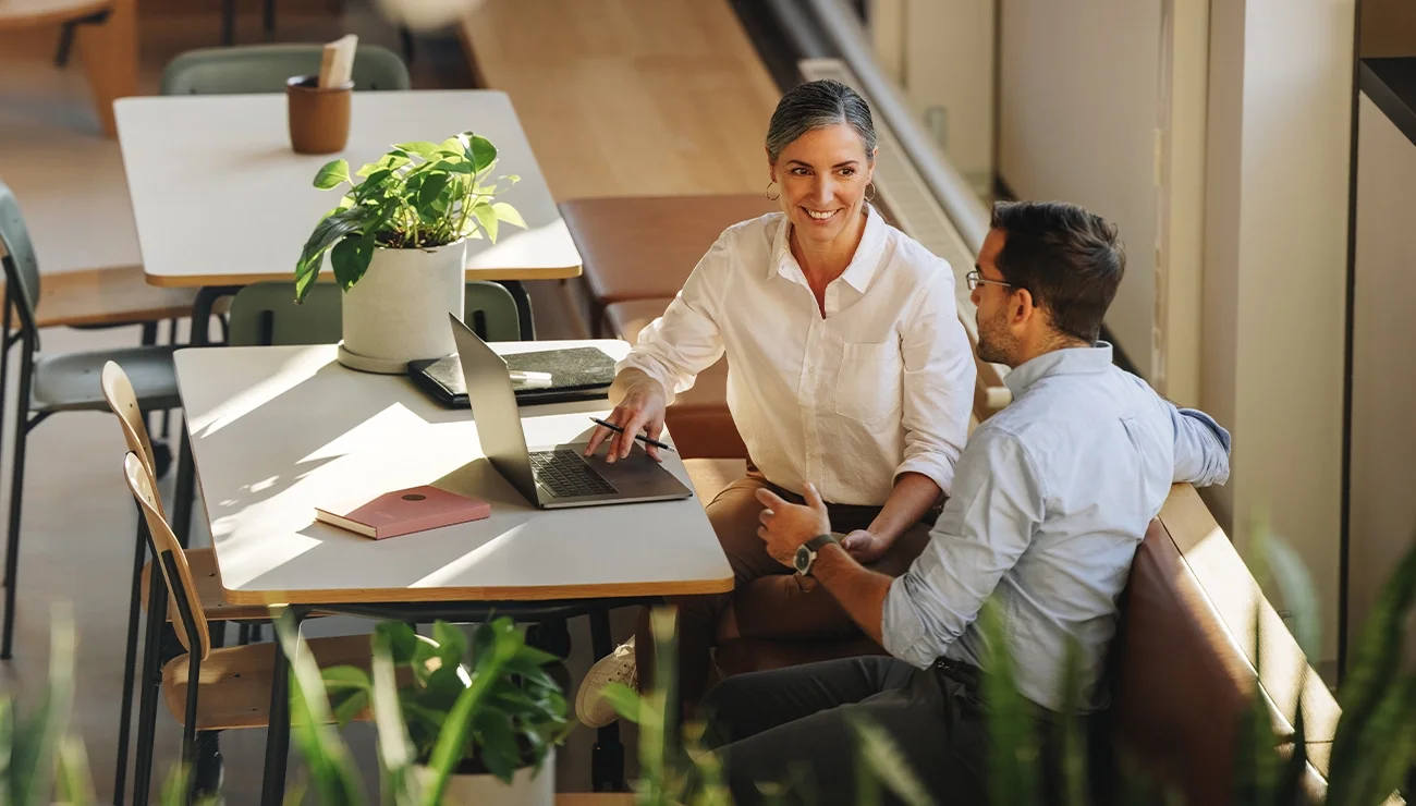 Twee collega's in gesprek aan tafel met laptop