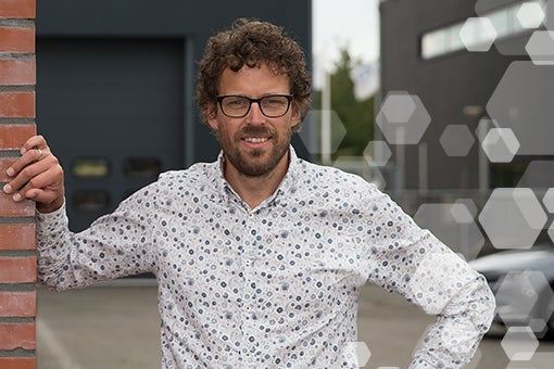 Docent Gert-Jan van Silfhout leunend tegen een muurtje voor een garage