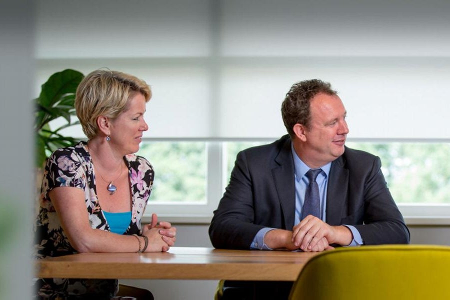 Vrouw en twee mannen in gesprek aan een vergadertafel
