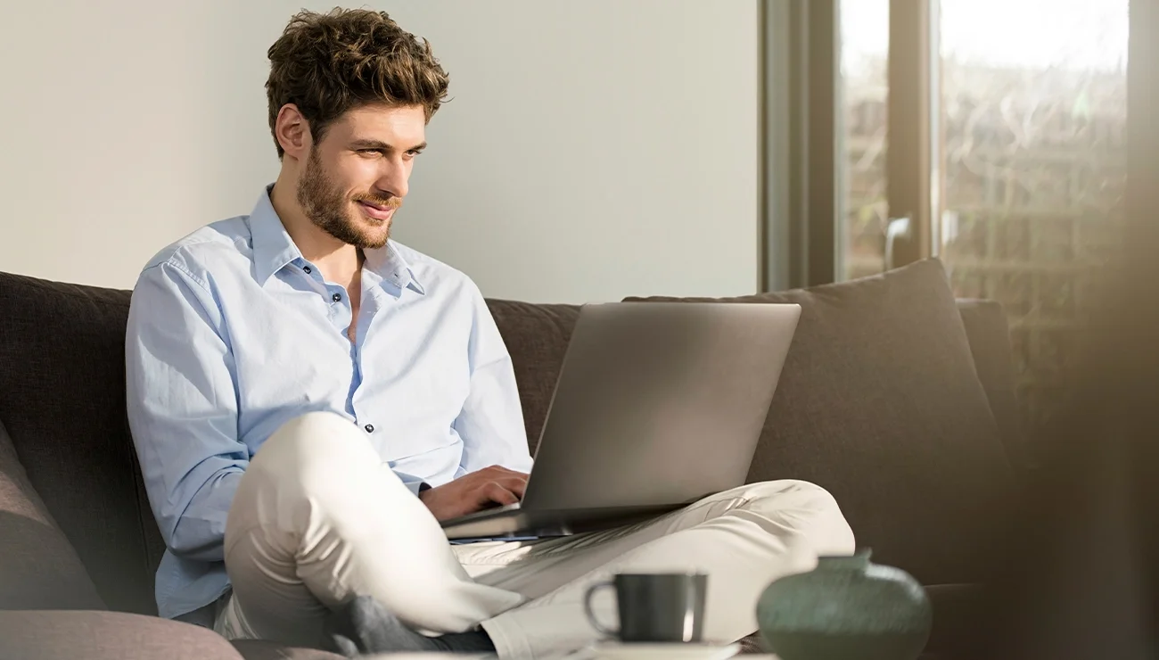 Man op bank met laptop op schoot