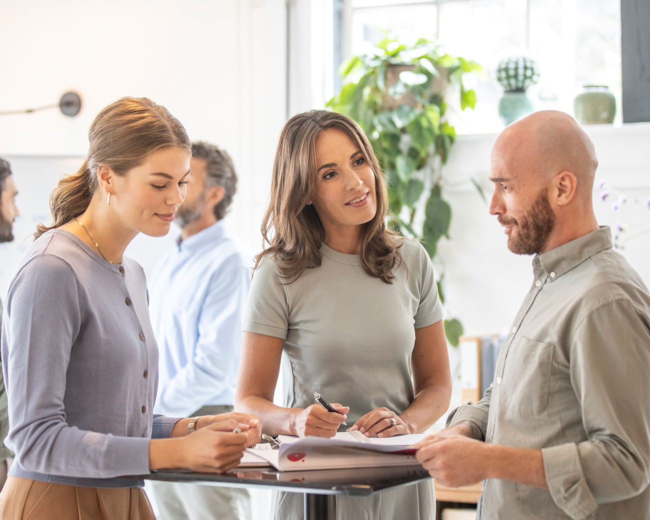 Drie personen in overleg aan een statafel