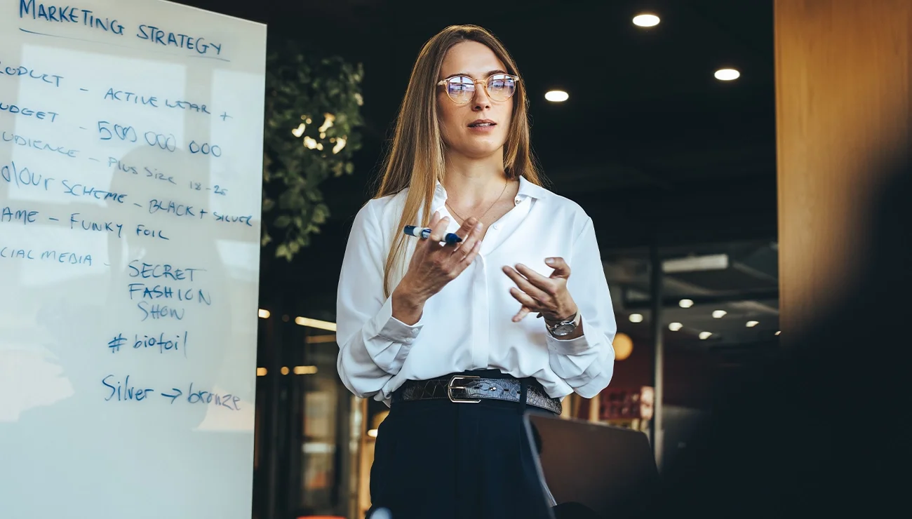 Vrouw staat voor een groep mensen en spreekt tijdens een presentatie