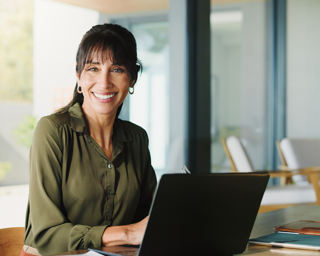 Vrolijke competente vrouw achter laptop in kantooromgeving