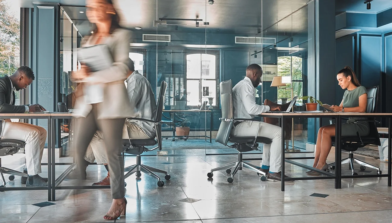 Open kantoorruimte met bureaus, computers en mensen die werken