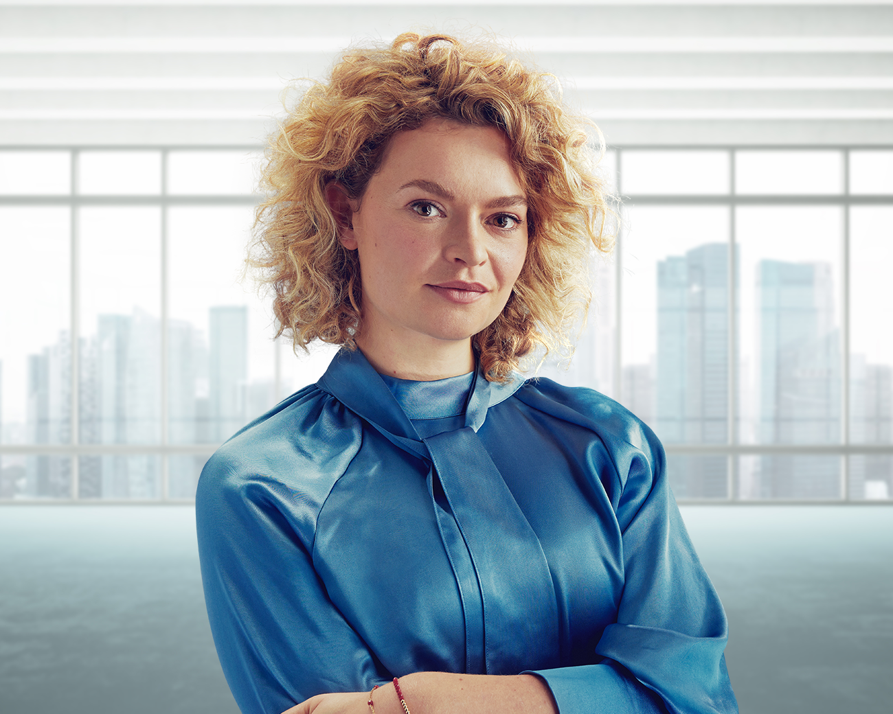Zakelijke vrouw met blauwe blouse in zakelijke omgeving met hoge gebouwen op achtergrond.