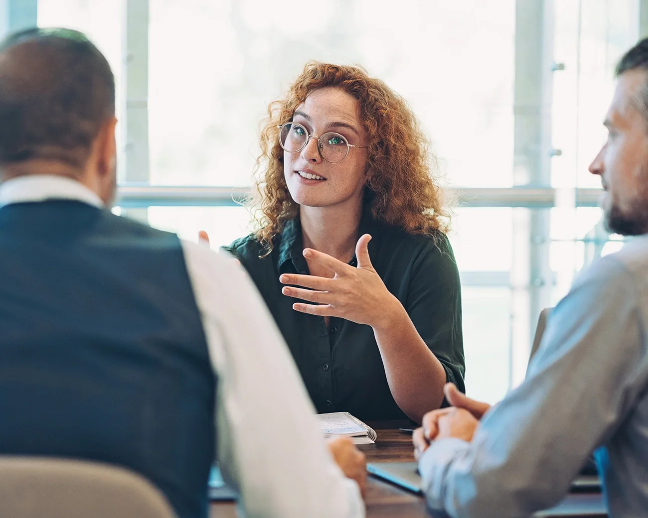 Vrouw met bril aan tafel in gesprek met collega's