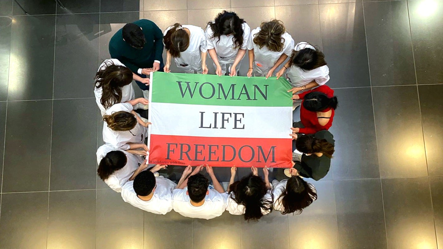 Mensen rond Iraanse vlag met tekst: "Woman Life Freedom"