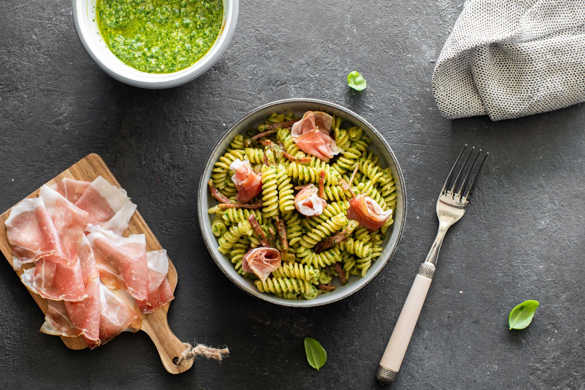 Piatto di fusilli con pesto di rucola e Speck Alto Adige IGP a fette.