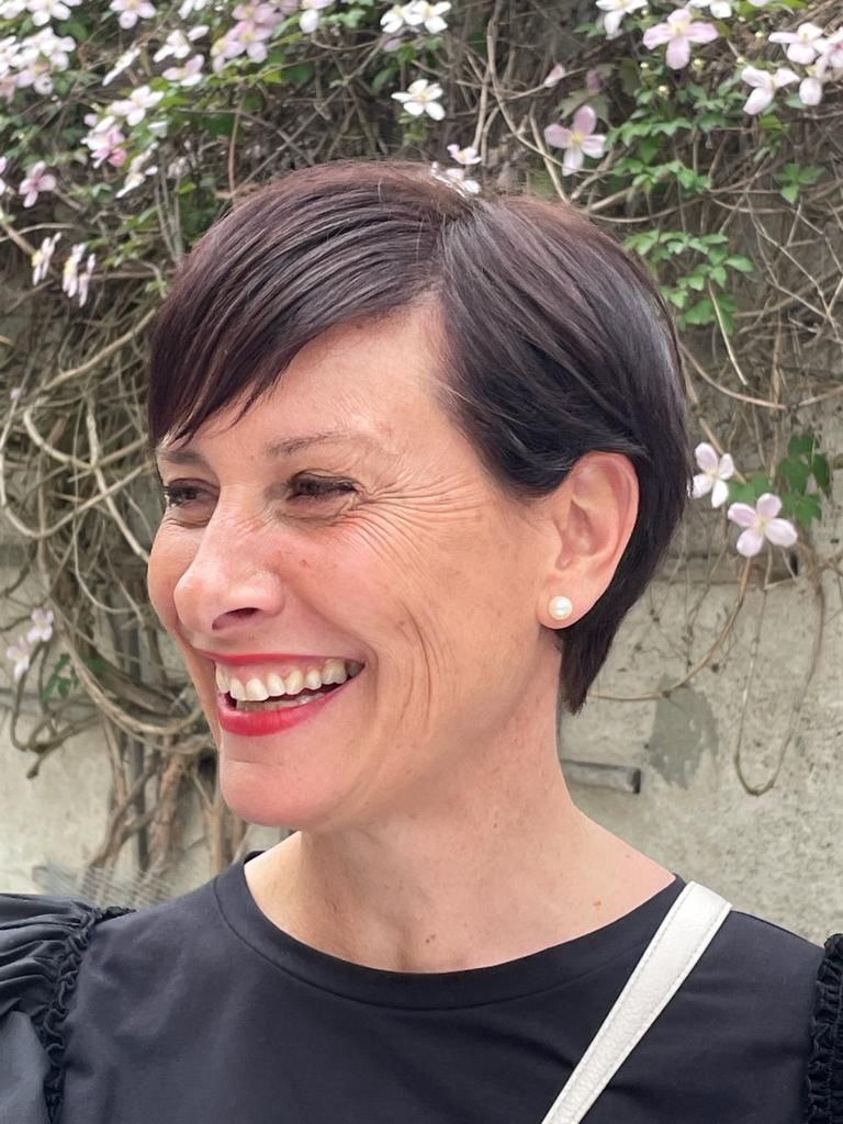 Verena Rungger lächelt vor einer Wand mit blühenden Kletterpflanzen