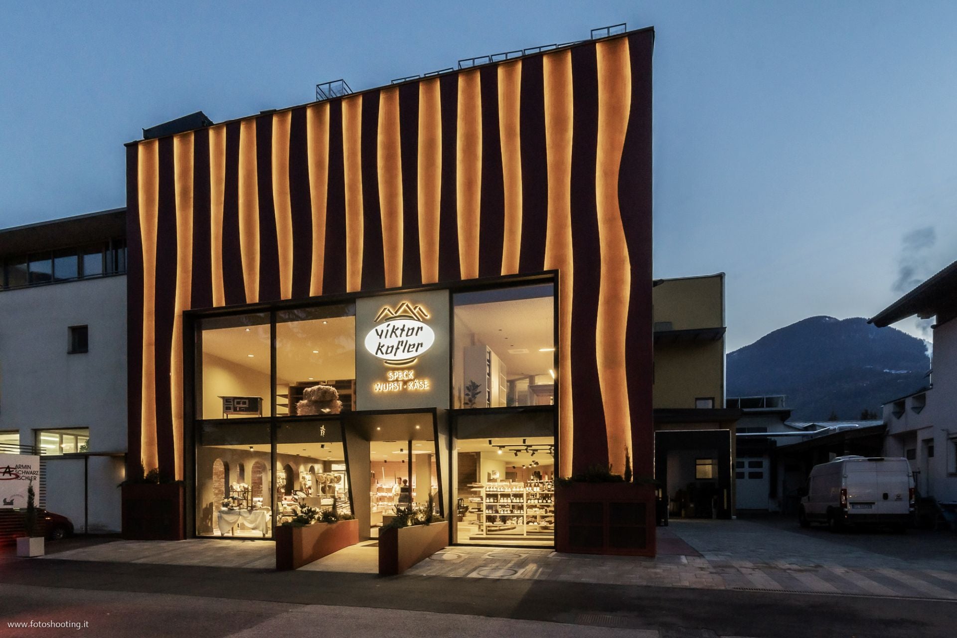 Gebäude des Viktor Kofler Geschäfts mit beleuchteter Fassade und Eingangsbereich bei Abendlicht