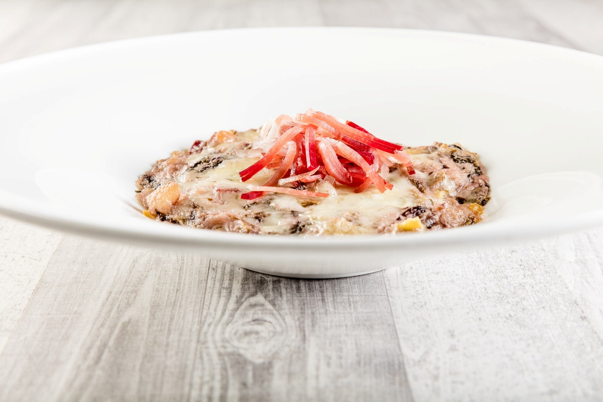 Gratinierte Radicchio-Lasagnette mit Südtiroler Speck g.g.A., überbacken mit geschmolzenem Käse.