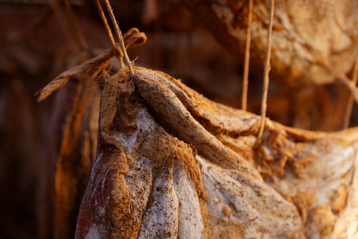 aufgehängtes Stück Südtiroler Speck g.g.A. während der Reifung in einem Lagerraum.