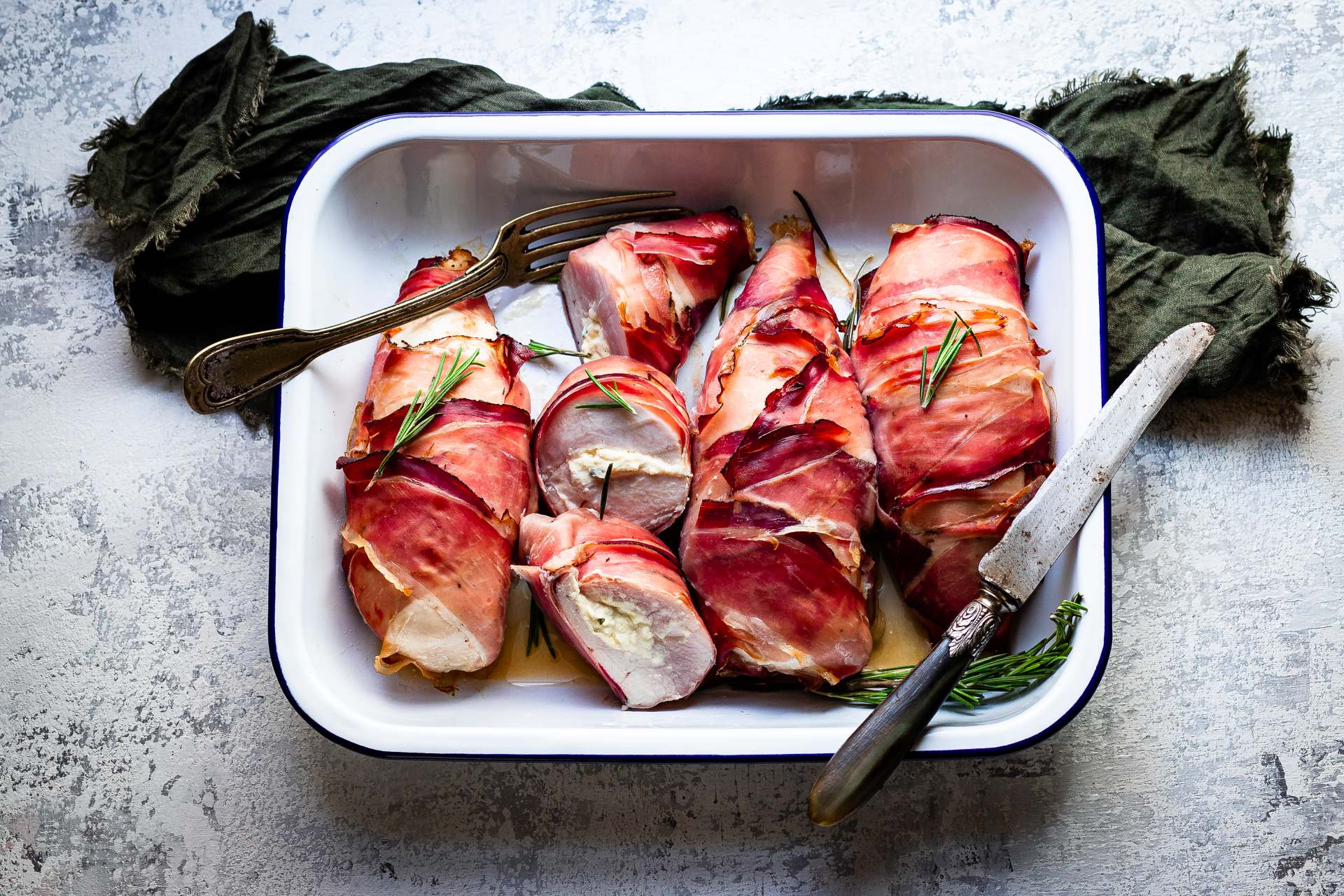 Gefüllte Hähnchenbrust in Südtiroler Speck g.g.A. gewickelt, mit Rosmarinzweigen