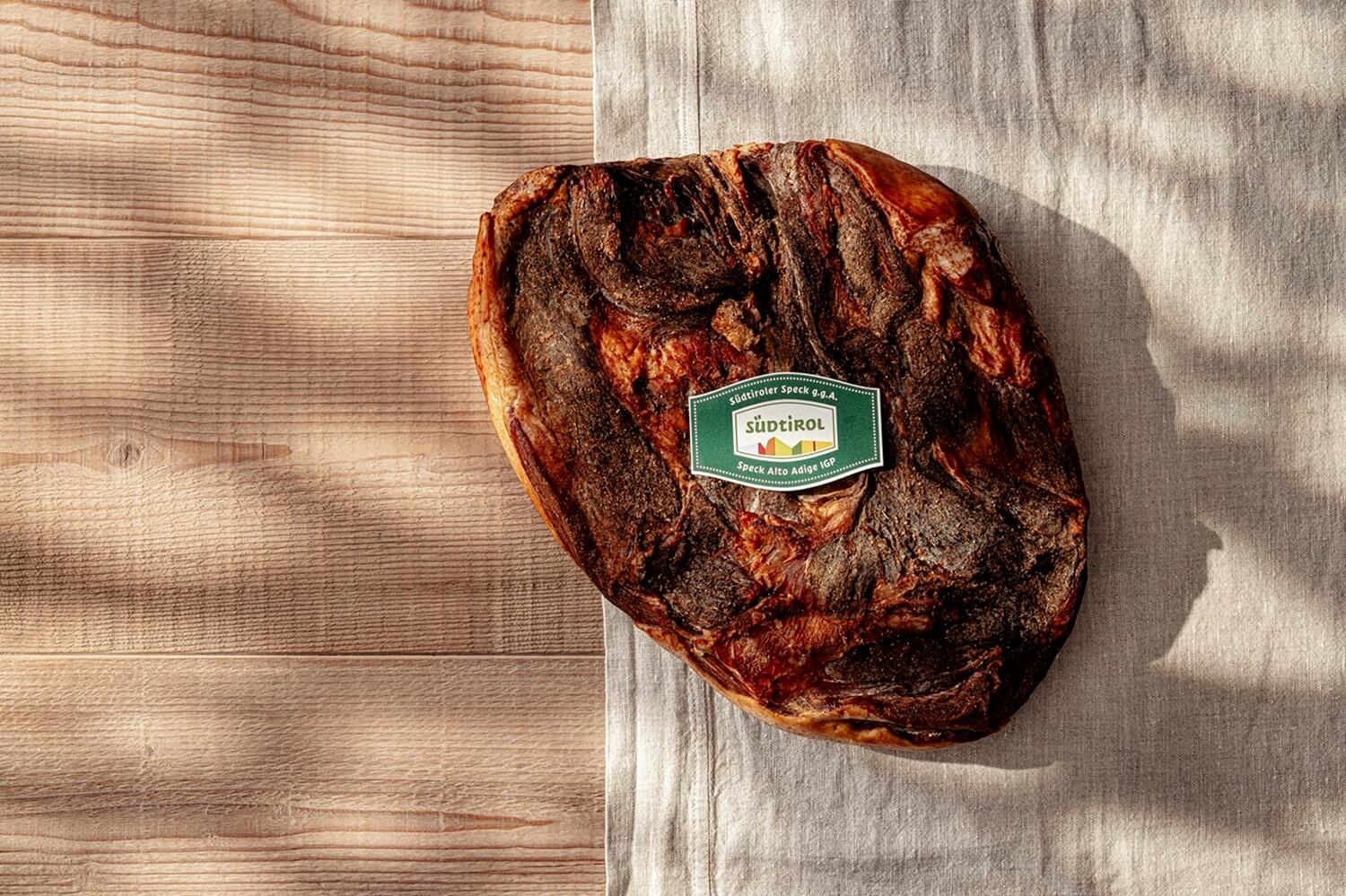 Ganzes Stück Südtiroler Speck g.g.A. auf Tuch mit Qualitätszeichen Südtirol.