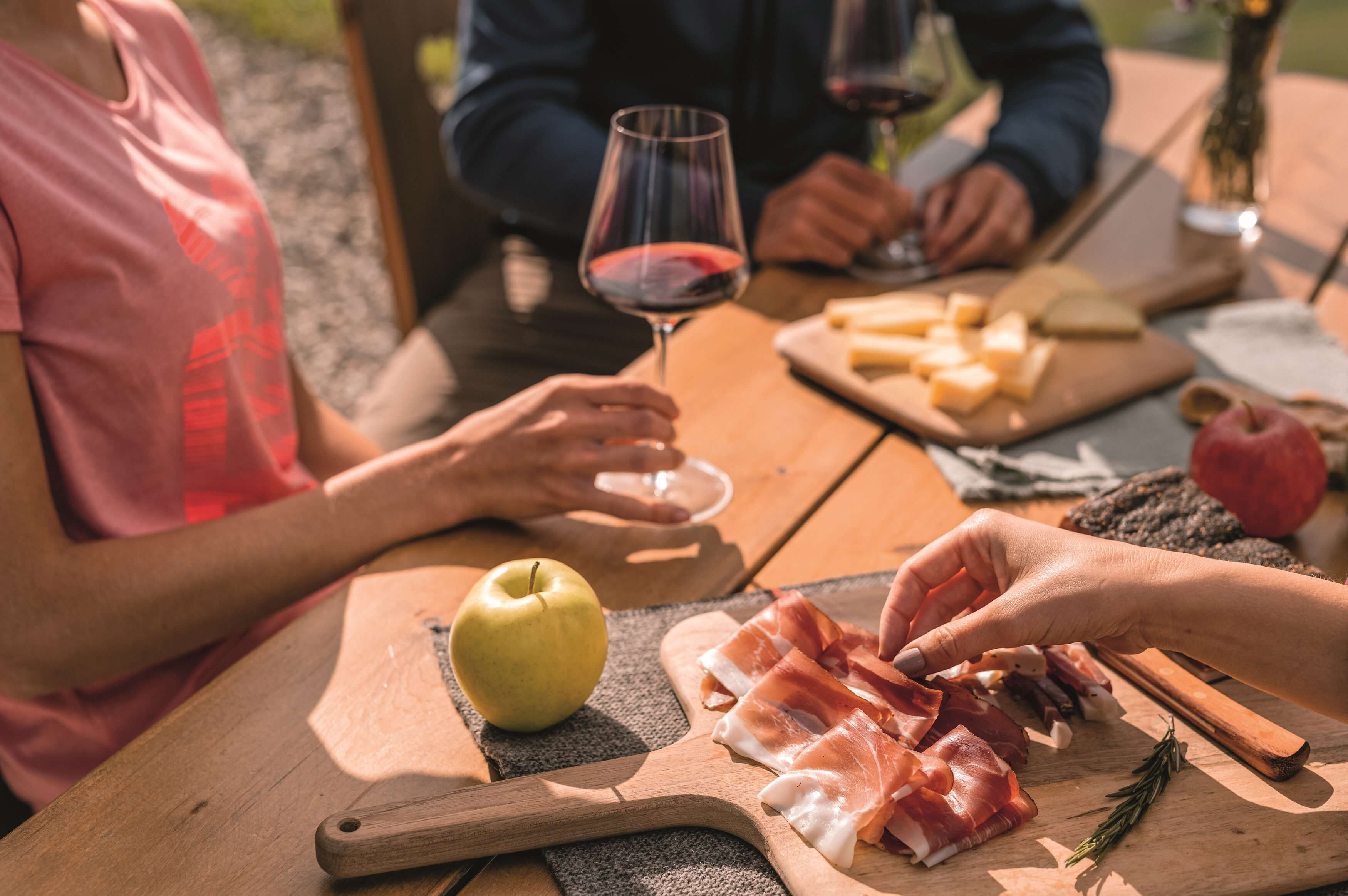 Holztisch mit Südtiroler Produkten und aufgeschnittenem Südtiroler Speck g.g.A.