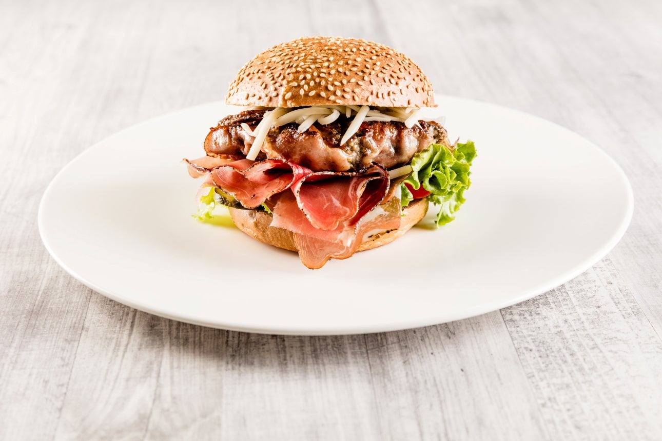 Sesamsamenbrötchen, Rindfleischburger, Südtiroler Speck g.g.A., Meerrettich, Zwiebel, Salat und Tomaten