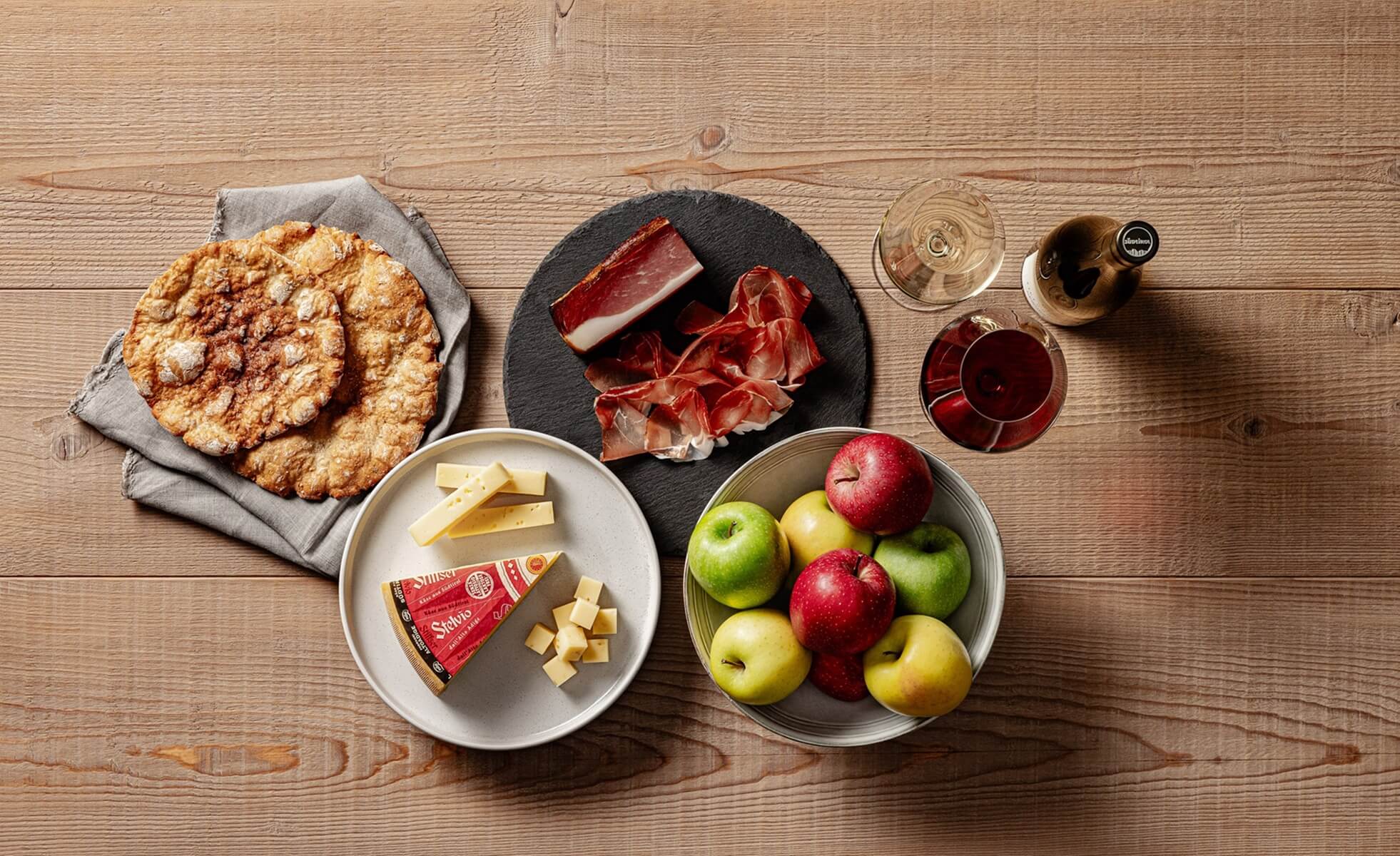 Teller mit Südtiroler Qualitätsprodukten wie Schüttelbrot, Speck, Käse, Äpfeln und Wein