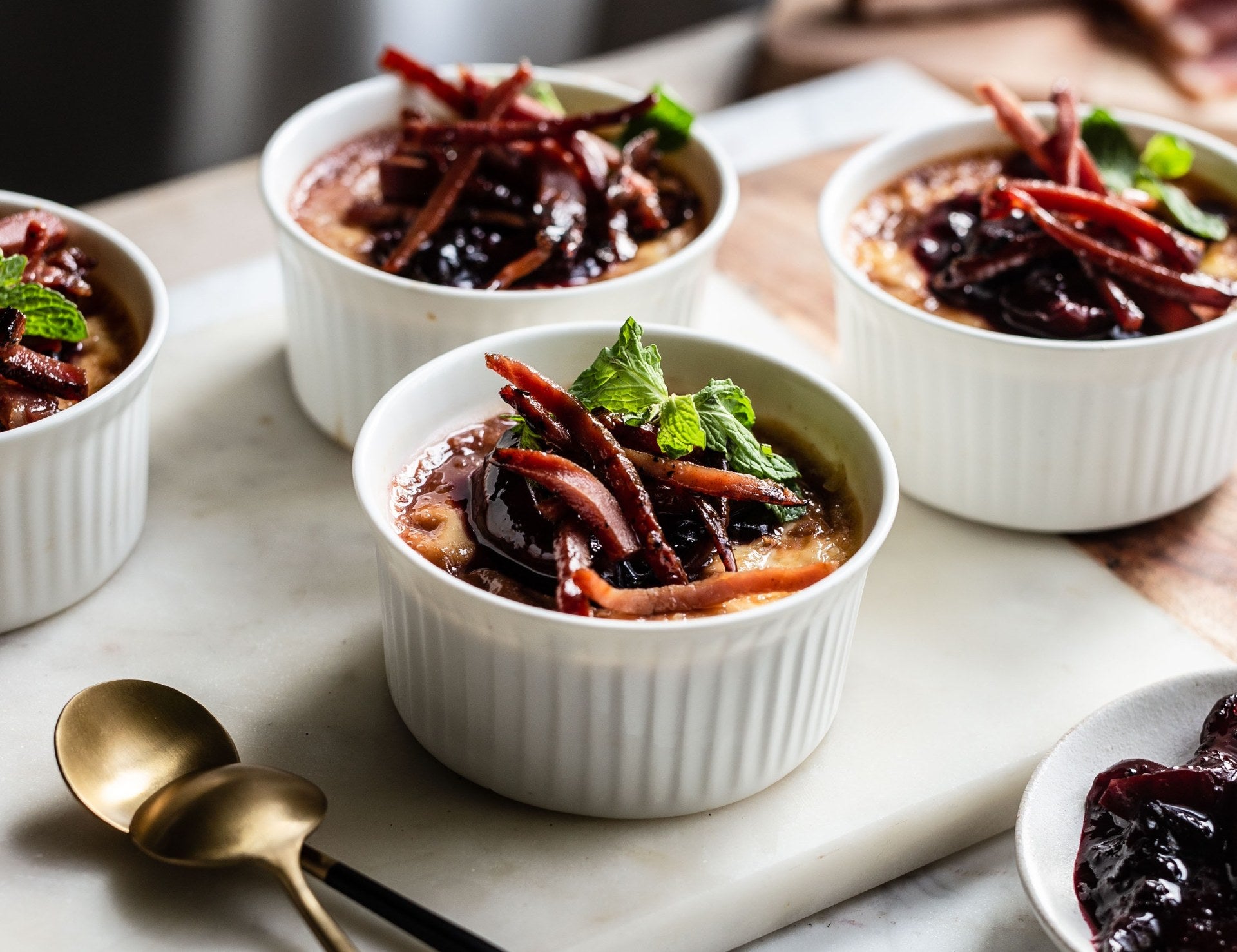 Crème brûlée, garniert mit Zwetschgensauce, knusprigem Südtiroler Speck g.g.A. und Minzblättern.