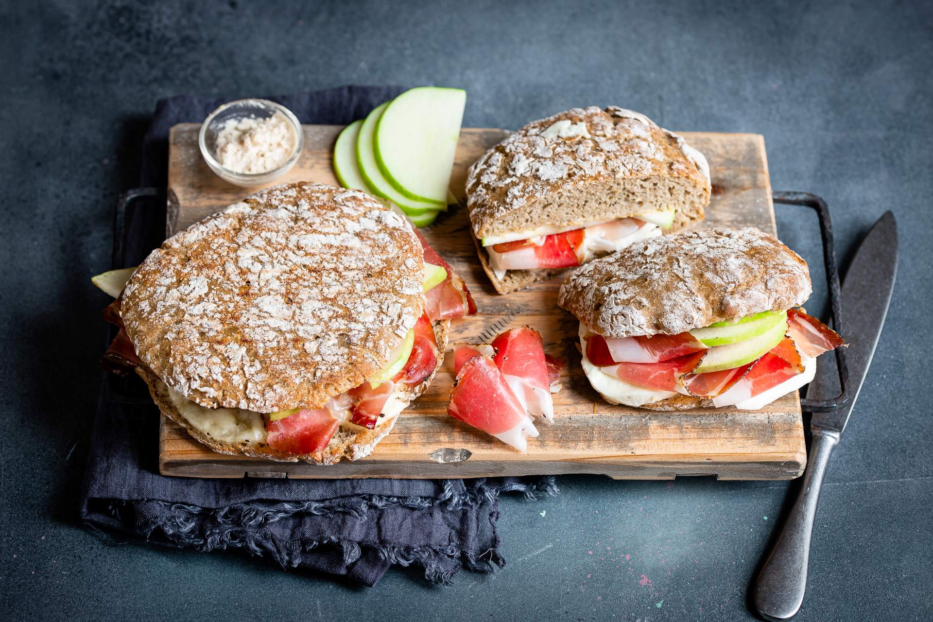 Bauerntoast mit Roggenlaibchen, Südtiroler Speck g.g.A., Mozzarella, Senf, Granny Smith-Äpfeln aus Südtirol und Gewürzgurken.