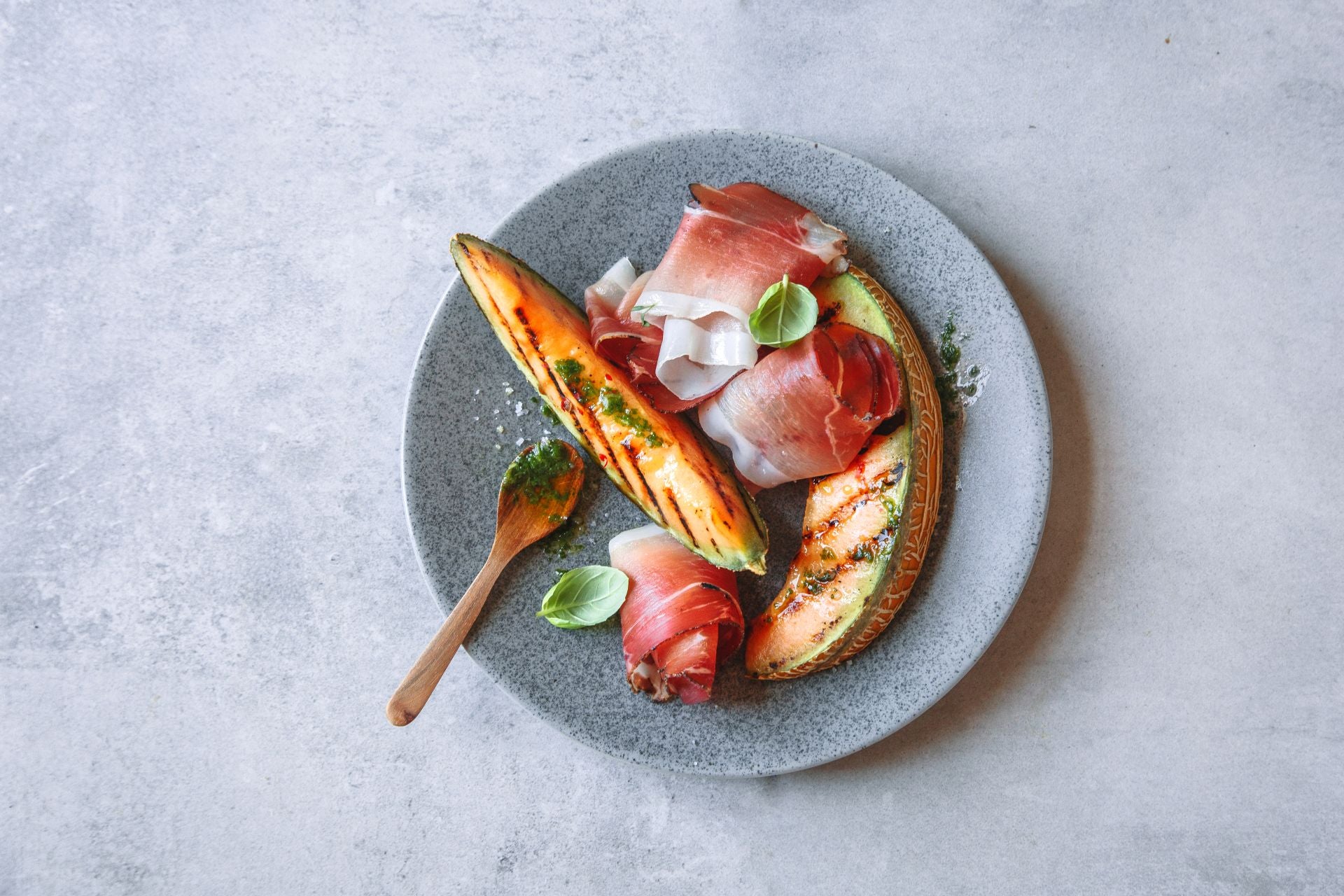 Gegrillte Melonenscheiben, serviert mit gerolltem Südtiroler Speck g.g.A.