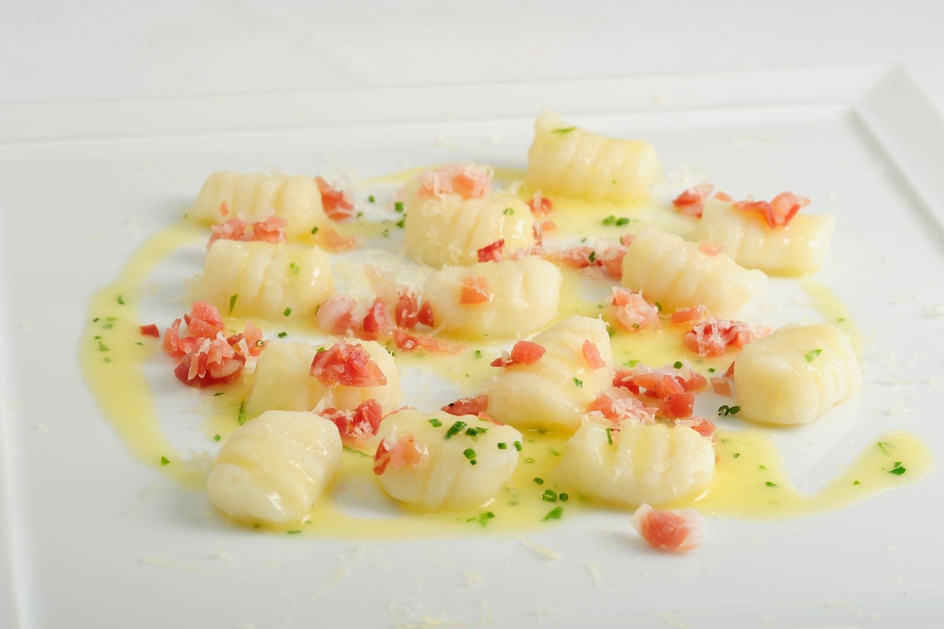Potato gnocchi served in a creamy speck sauce, topped with South Tyrolean speck and fresh chives.