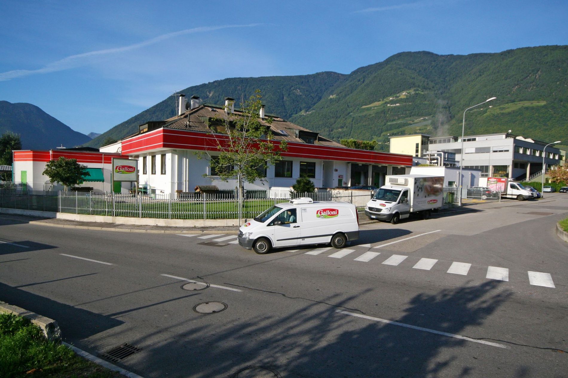 Gebäude des Galloni Standorts an Straße mit Lieferwagen und Berglandschaft im Hintergrund