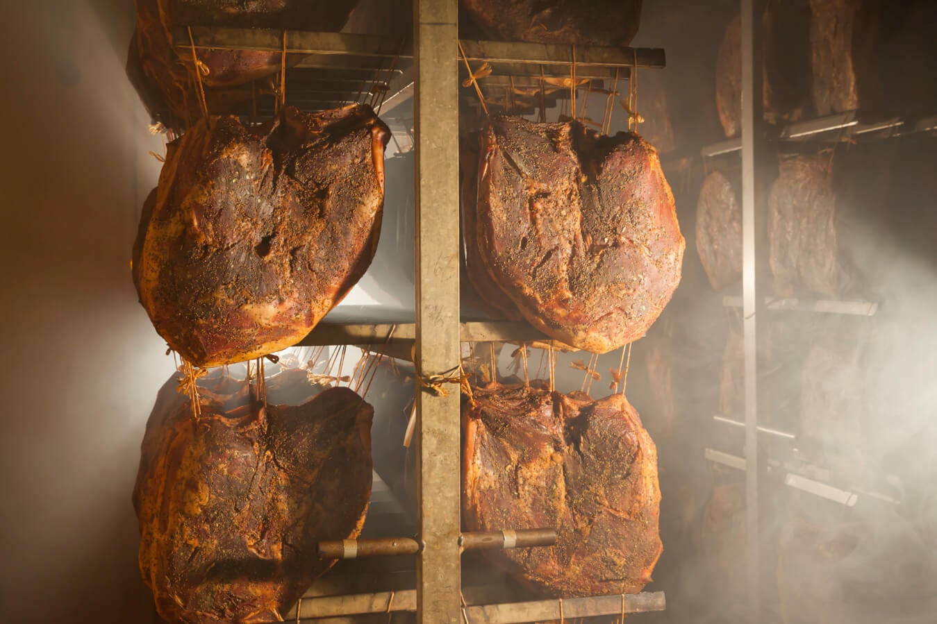 Südtiroler Speck g.g.A. bei der Räucherung im Reiferaum aufgehängt