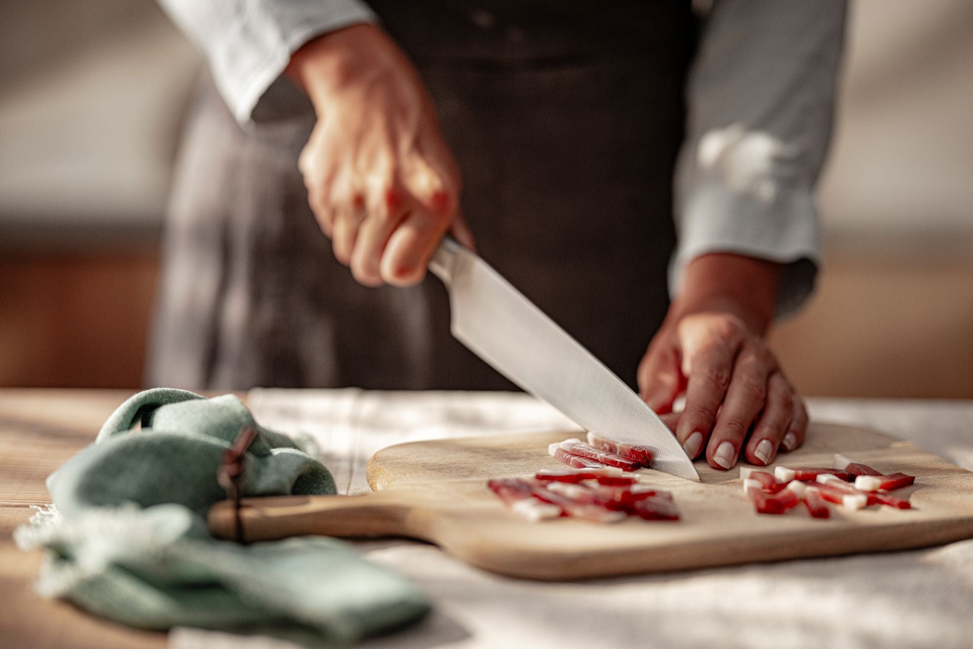Personne coupe Speck Alto Adige IGP en lamelles sur planche en bois avec couteau.