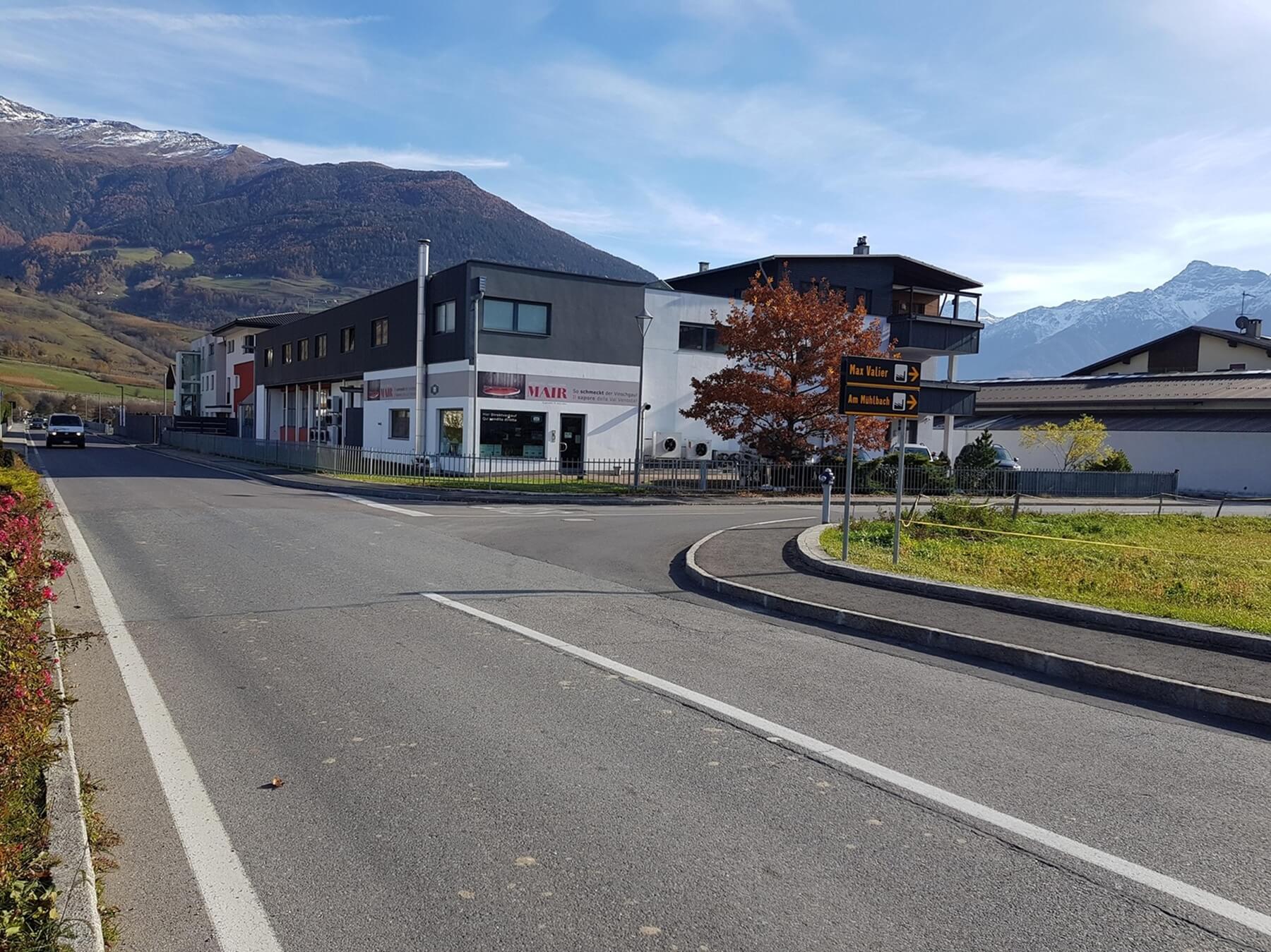 Gebäude des Mair Firmensitzes an Straße mit Bergen im Hintergrund und angrenzendem Vorplatz