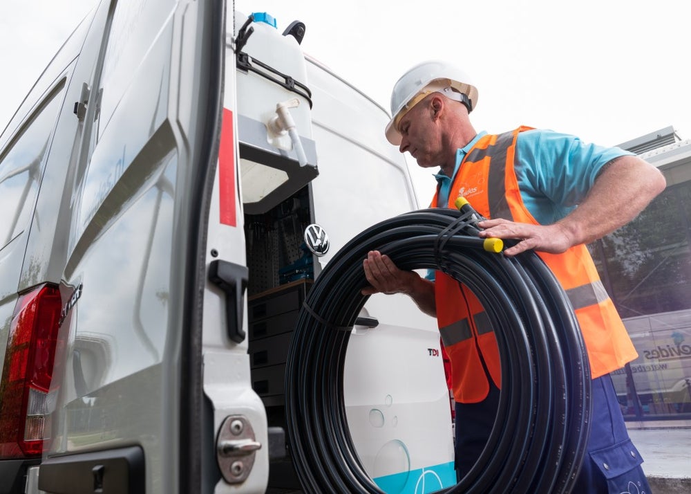 Monteur van Evides laadt rol leidingen in een bus.
