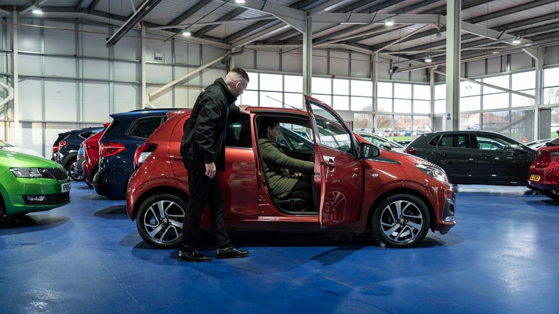 Lady in car in Motorpoint showroom with salesperson stood by car