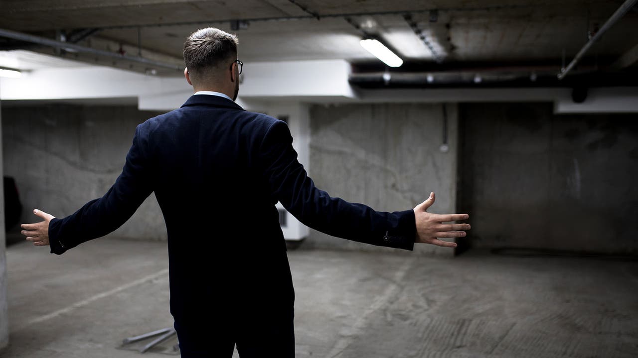 Man in suit is in obvious shock at an empty parking space where his car previously was