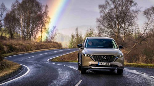 Mazda CX-5 driving front view, under rainbow