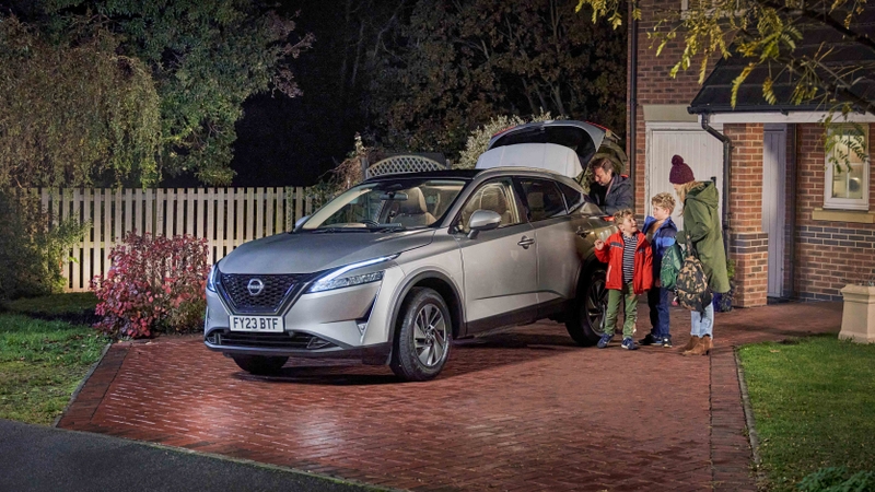 Family standing by Nissan Qashqai on driveway