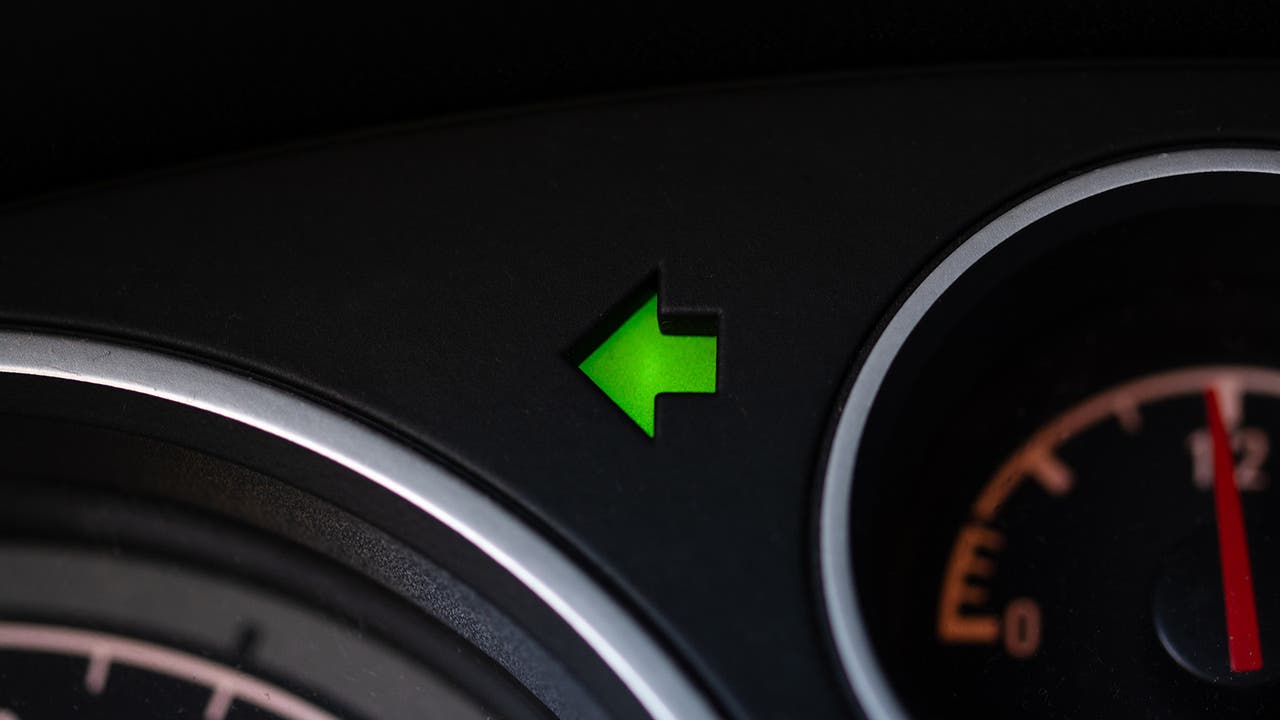 Closeup of illuminated left indicator light on dashboard