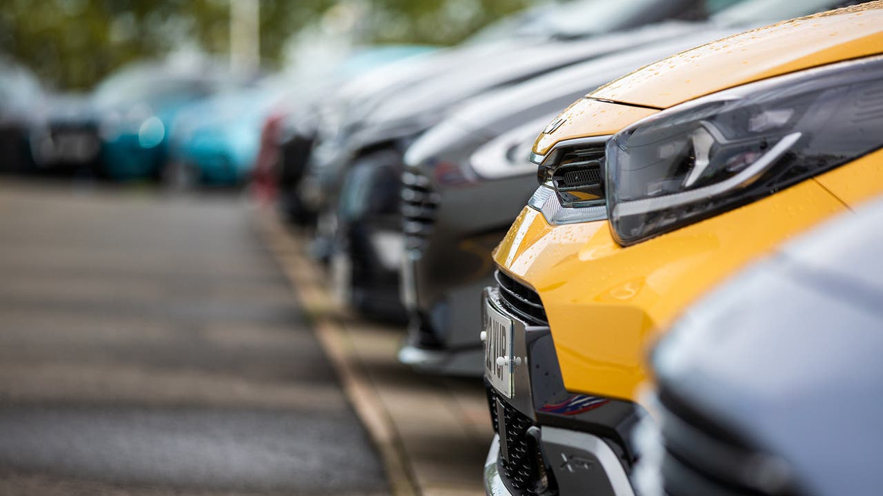 The nose of a yellow Kia Picanto sticks out among a row of nearly new cars at a Motorpoint store