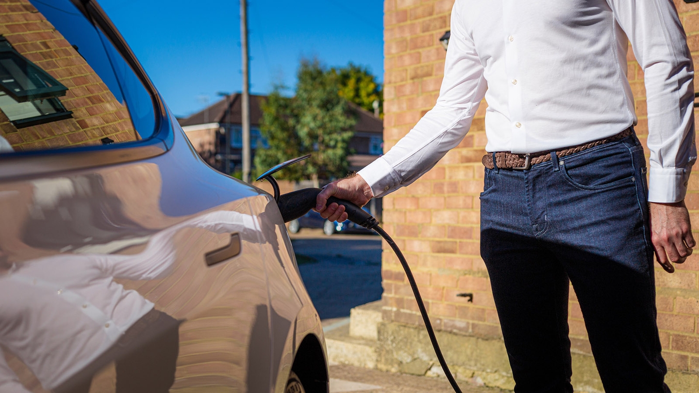 man connecting electric vehicle to charger outside home