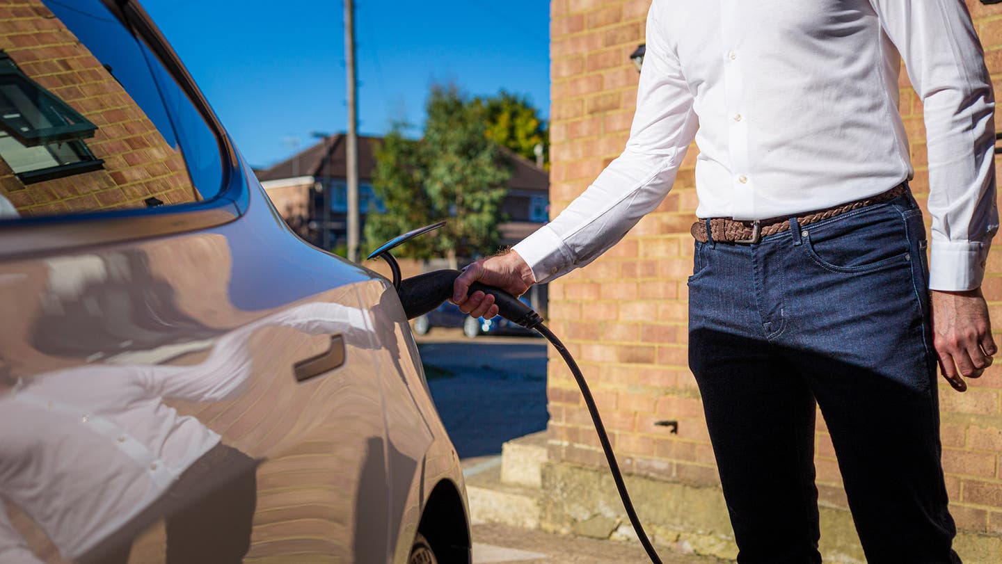 man connecting electric vehicle to charger outside home