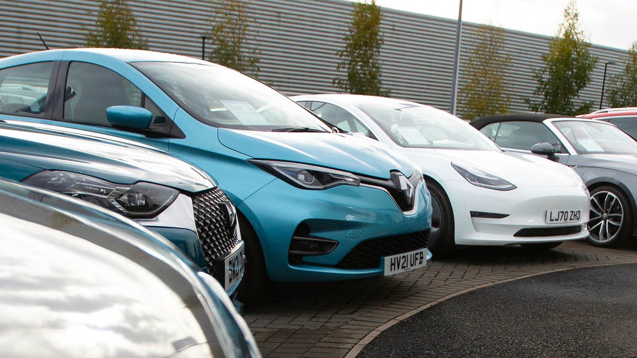 Blue Renault Zoe and white Tesla Model 3 parked in a row of cars outside a Motorpoint store