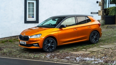 Orange Skoda Fabia parked on cobbles in front of white house