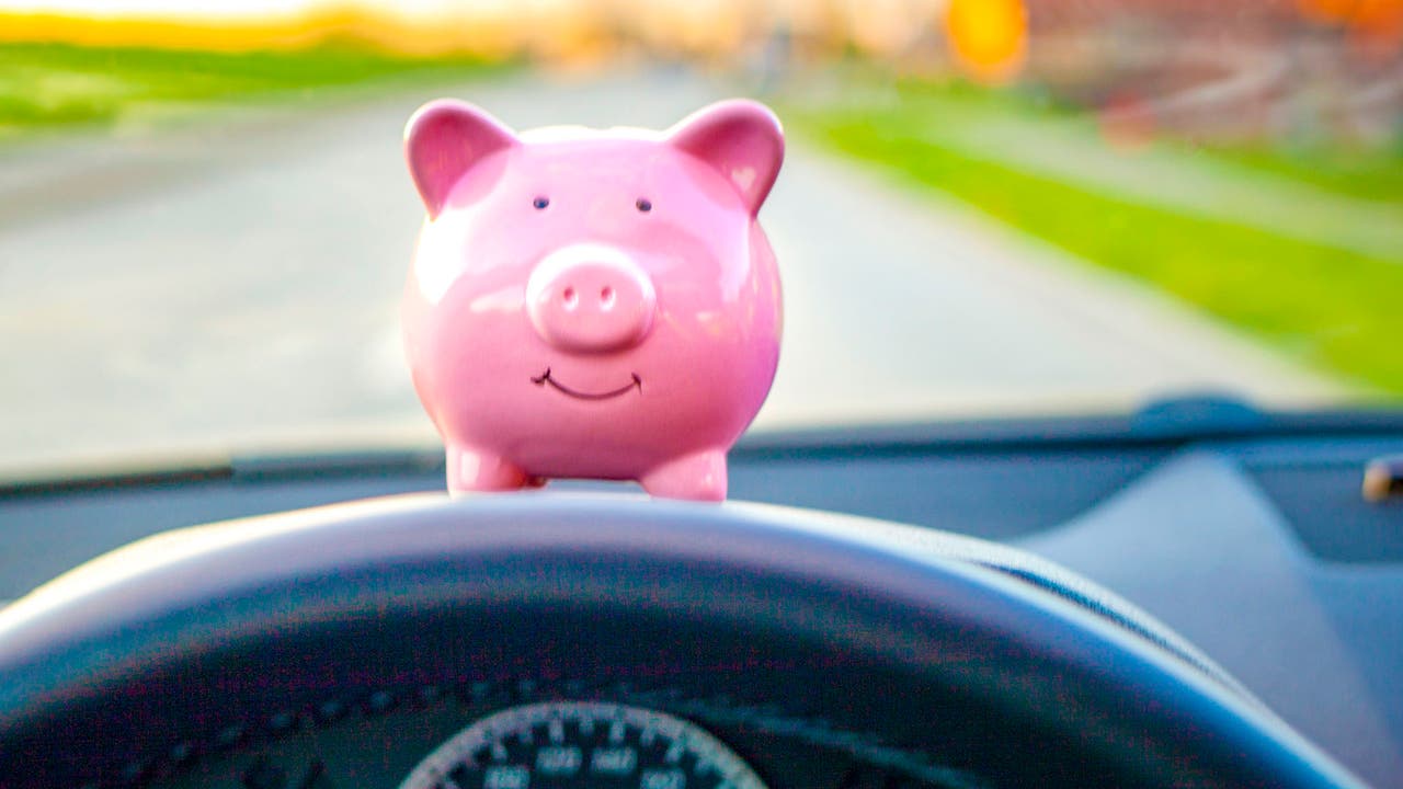 Pink piggybank on top of steering wheel