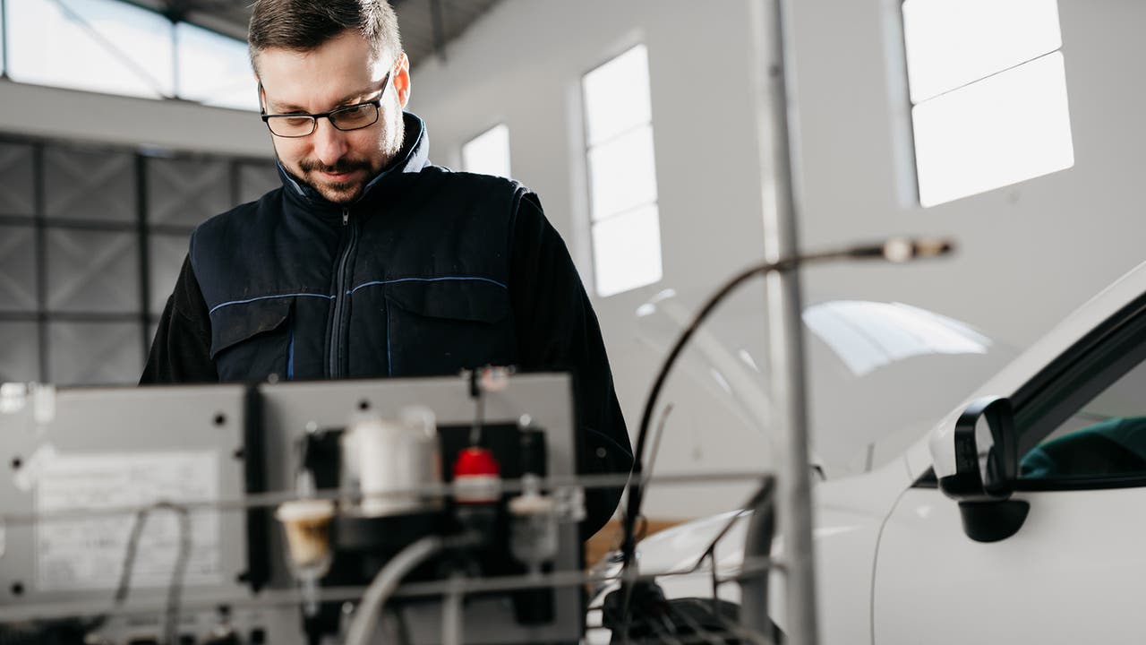 Car technician performs diagnostics on a car in a garage