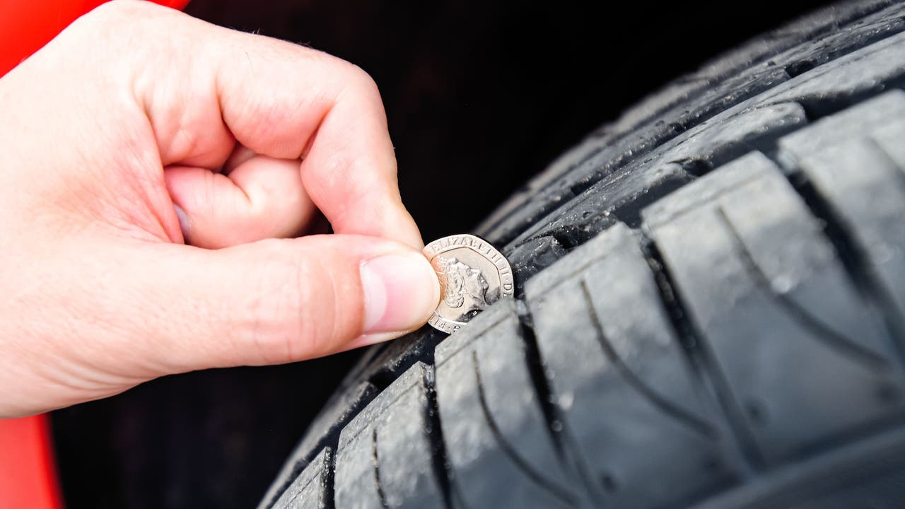 Person checking tyre tread depth with 20p coin