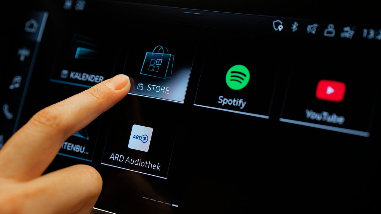 A person's finger hovers over the screen of an Audi infotainment system