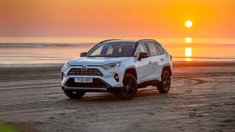 Toyota RAV4 in white, romantically positioned on a beach in front of a dramatic sunset