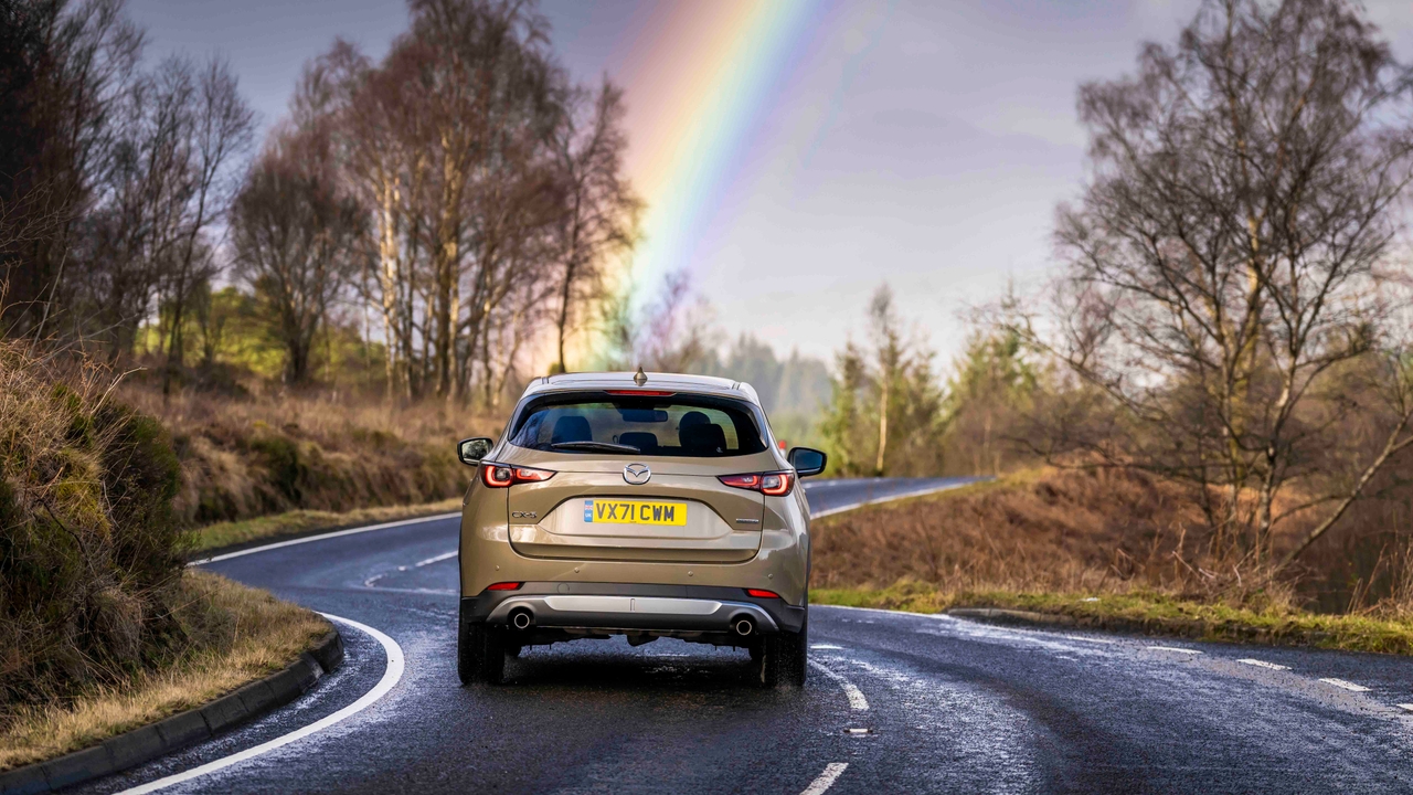 Mazda CX-5 driving rear view, under rainbow